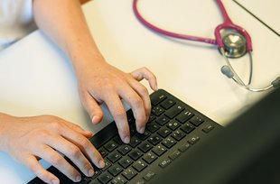 Ärztin schreibt auf der Tastatur